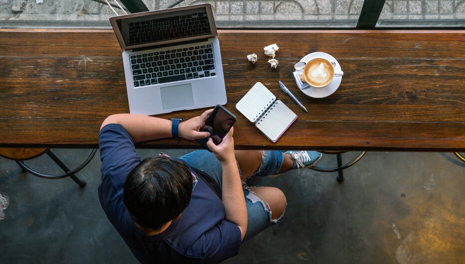 man sitting at laptop with phone