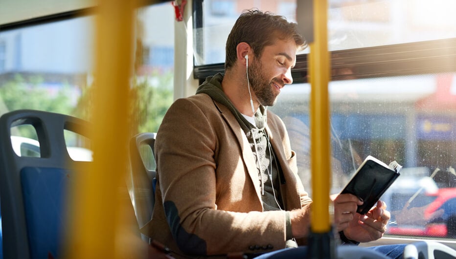 man reading a book while riding a bus