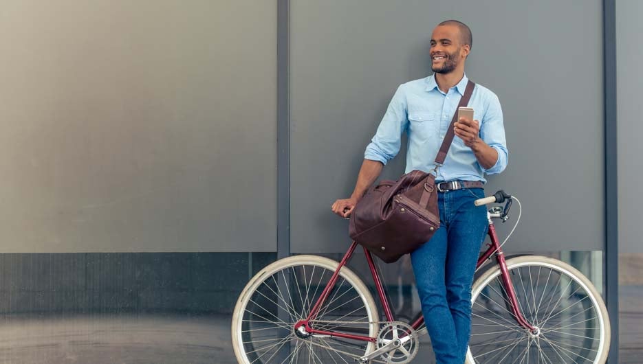 smiling man on his bicycle holding his mobile phone