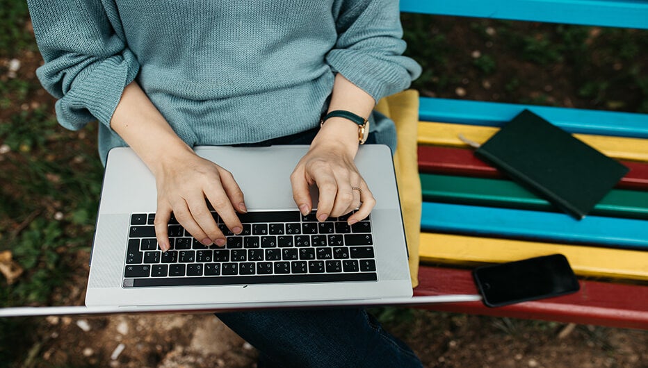 woman sitting on bench while using laptop