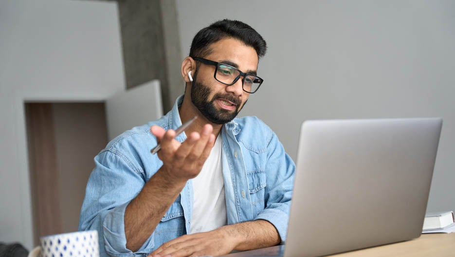man with glasses taking notes during video call