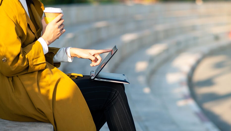 woman outside with laptop and coffee