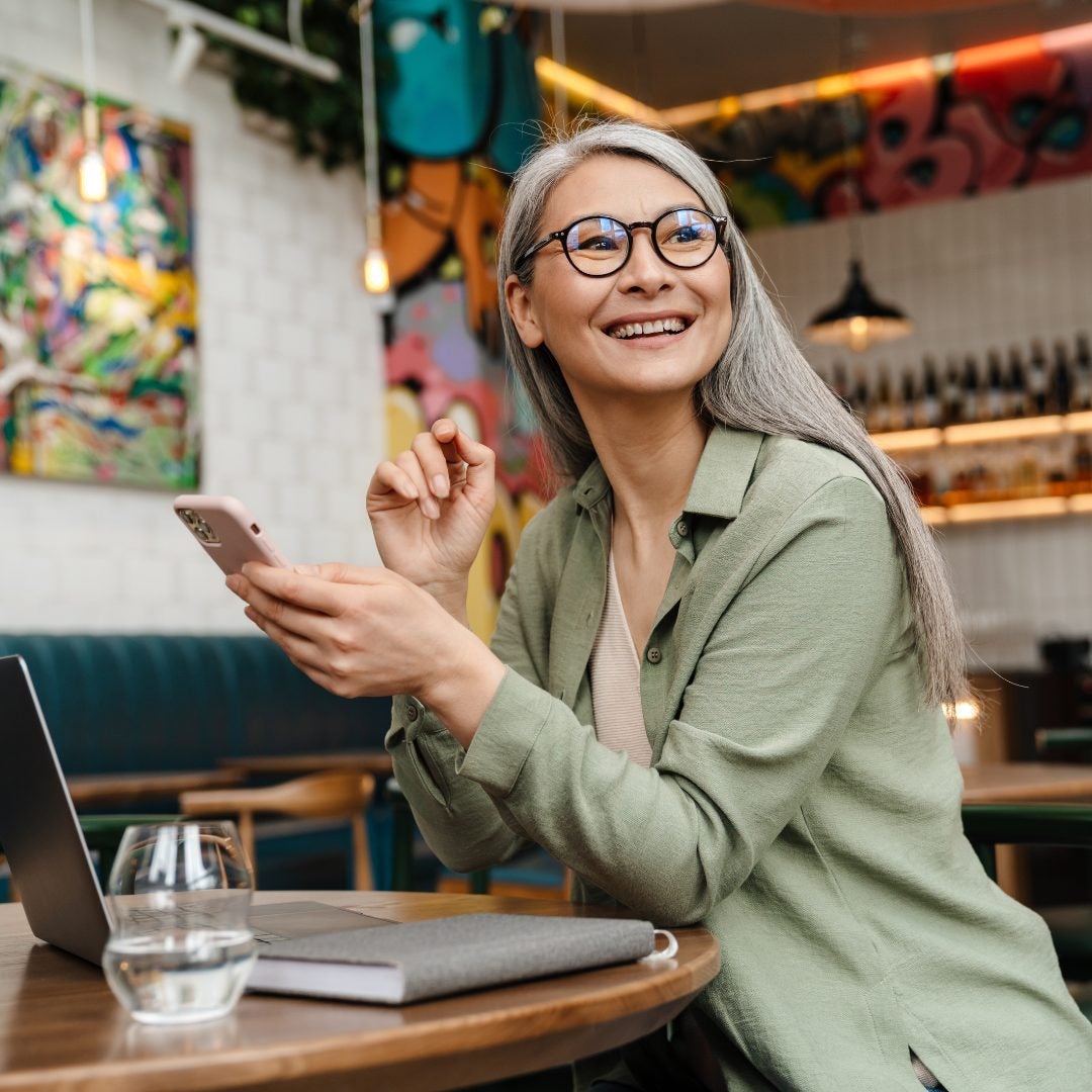 Smiling mature professional business woman bank manager, older happy female executive or lady entrepreneur holding digital tablet pad standing in office at work, looking away at copy space.